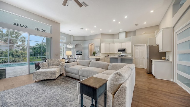 living room featuring a high ceiling, light hardwood / wood-style flooring, and ceiling fan