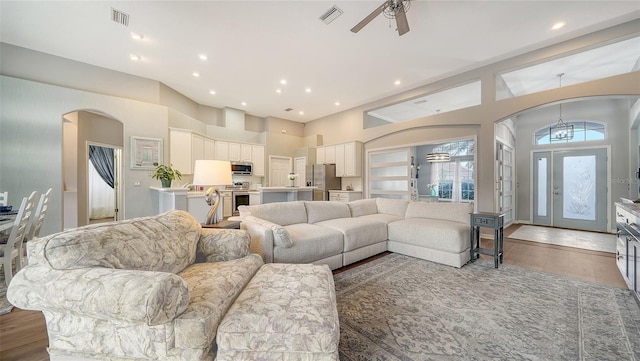 living room with hardwood / wood-style floors, ceiling fan, and a towering ceiling