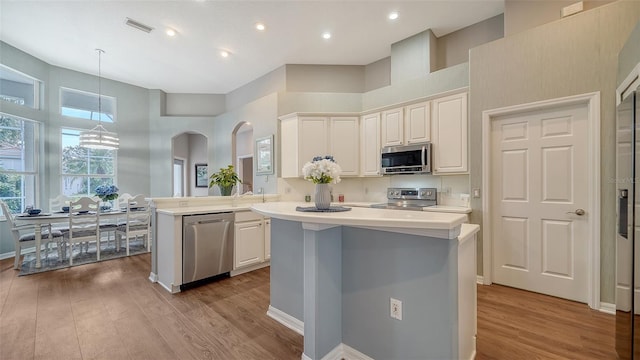8334 Sailing Loop, Lakewood Ranch, FL 34202 - kitchen featuring appliances with stainless steel finishes, light countertops, light wood-style flooring, a center island, and a high ceiling