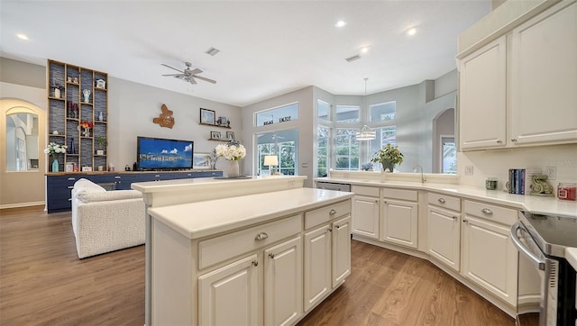 kitchen featuring stainless steel range with electric stovetop, ceiling fan, a center island, and light wood-type flooring