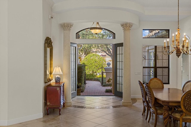 foyer entrance with decorative columns, light tile patterned floors, and a chandelier