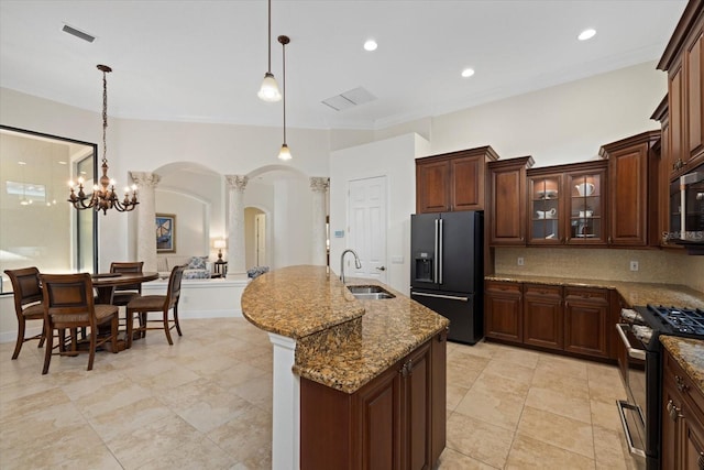 kitchen with high quality fridge, stainless steel gas range oven, sink, a center island with sink, and a chandelier