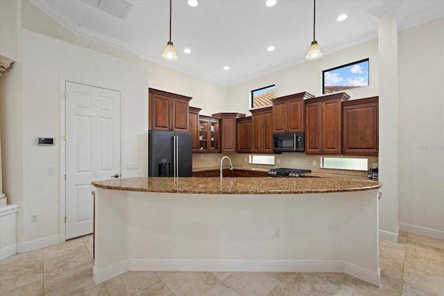 kitchen featuring high quality fridge, stone counters, pendant lighting, and a large island