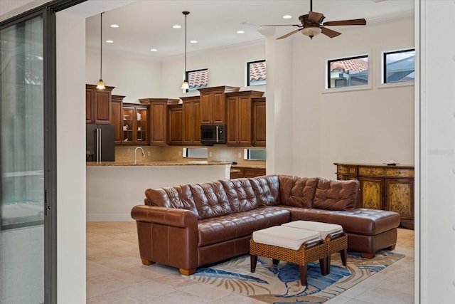 living room featuring ceiling fan, ornamental molding, sink, and light tile patterned floors