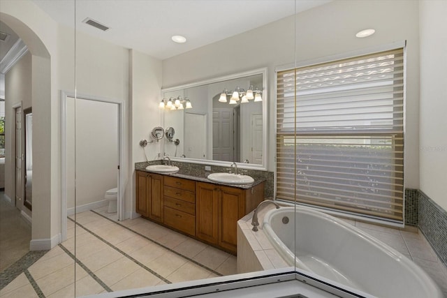 bathroom with tile patterned floors, tiled tub, vanity, and toilet