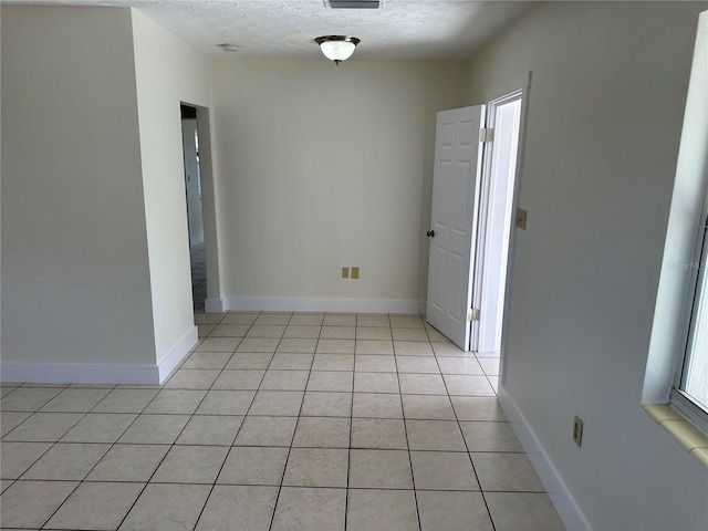 tiled spare room with a textured ceiling