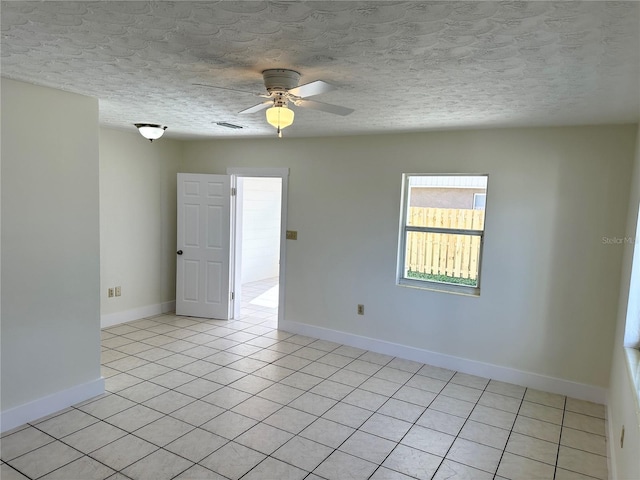 tiled empty room featuring a textured ceiling and ceiling fan