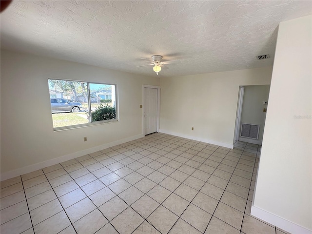 spare room featuring a textured ceiling, ceiling fan, and light tile patterned flooring