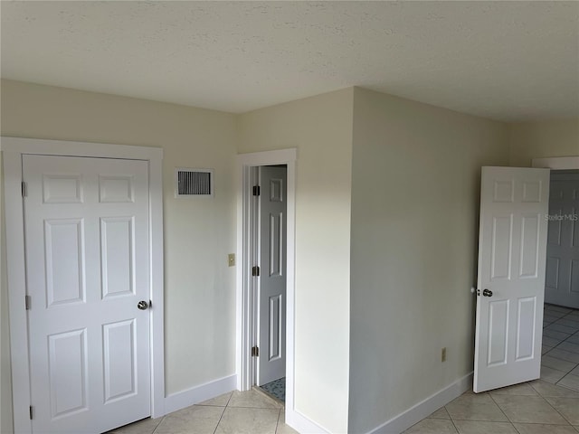 unfurnished bedroom with light tile patterned floors and a textured ceiling