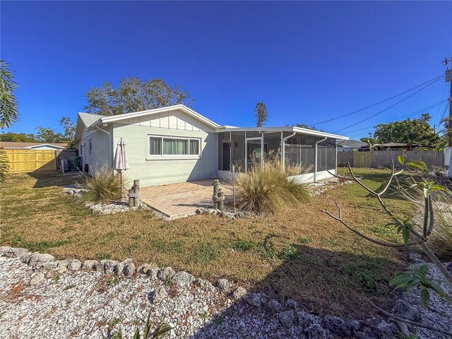 back of property with a sunroom and a yard