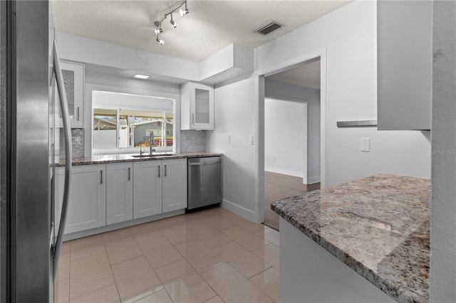 kitchen featuring light stone counters, a sink, white cabinets, appliances with stainless steel finishes, and visible vents
