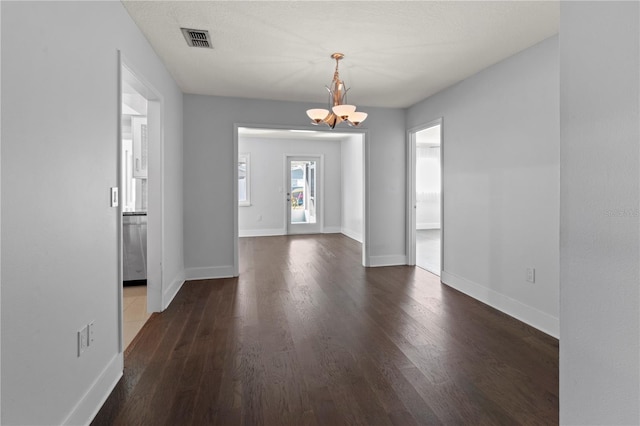 unfurnished dining area with a chandelier, wood finished floors, visible vents, and baseboards