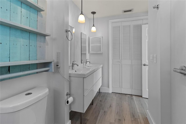 bathroom with wood finished floors, visible vents, toilet, vanity, and baseboards