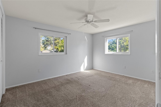 carpeted empty room featuring baseboards and a ceiling fan