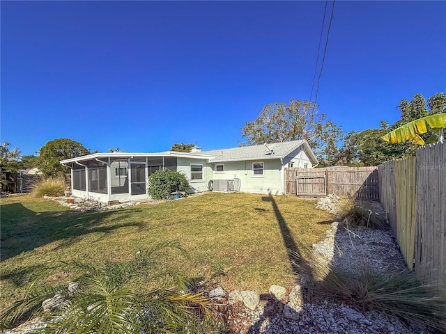 back of property featuring a lawn, a fenced backyard, and a sunroom