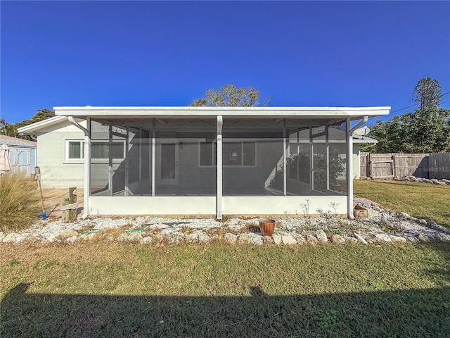 back of house with a sunroom, fence, and a lawn