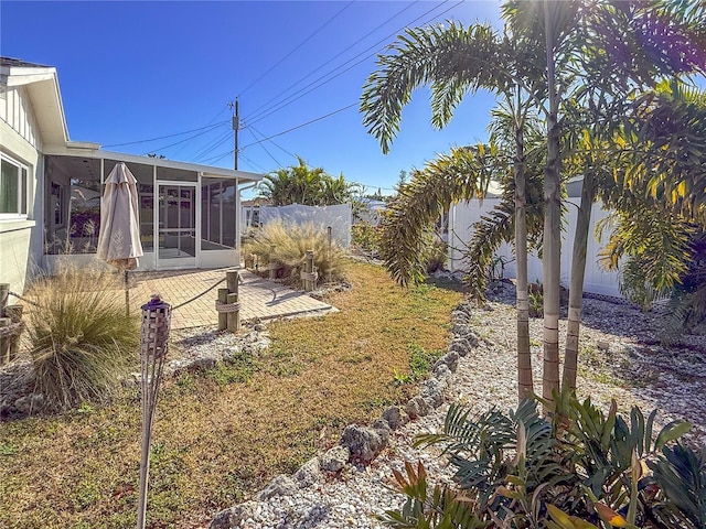 view of yard with a fenced backyard, a sunroom, and a patio