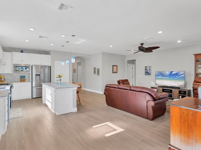 kitchen with a center island, pendant lighting, a breakfast bar area, white cabinets, and appliances with stainless steel finishes