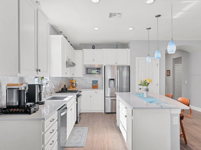 kitchen with white cabinetry, sink, decorative light fixtures, and appliances with stainless steel finishes