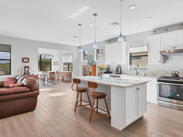 kitchen featuring white cabinetry, a center island, hanging light fixtures, electric stove, and light wood-type flooring