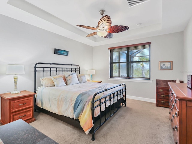 carpeted bedroom featuring ceiling fan and a raised ceiling