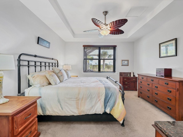 bedroom with light carpet, a tray ceiling, and ceiling fan