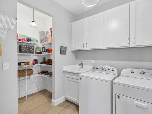 laundry area with cabinets, light wood-type flooring, sink, and washing machine and clothes dryer