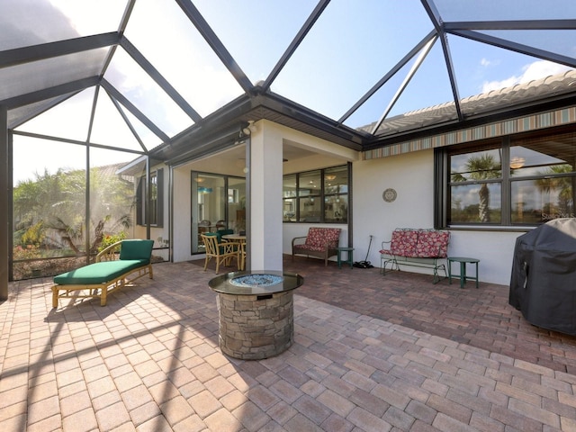 view of patio / terrace featuring glass enclosure, area for grilling, and a fire pit