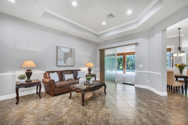 living room featuring a chandelier, a raised ceiling, a wealth of natural light, and ornamental molding