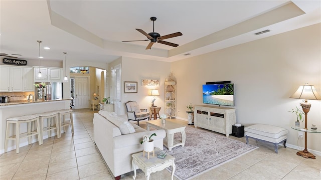 living room with ceiling fan, light tile patterned floors, sink, and a tray ceiling