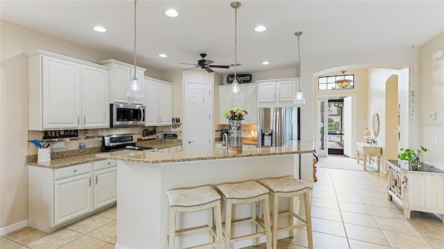 kitchen with tasteful backsplash, stainless steel appliances, ceiling fan, decorative light fixtures, and white cabinets