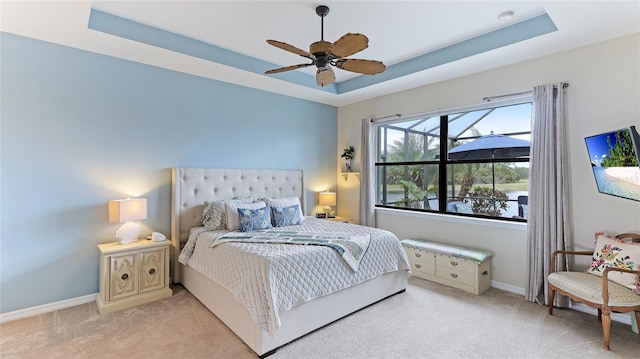 bedroom featuring ceiling fan, light carpet, and a tray ceiling