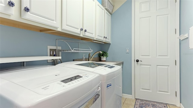 laundry area featuring cabinets, light tile patterned floors, sink, and washing machine and clothes dryer