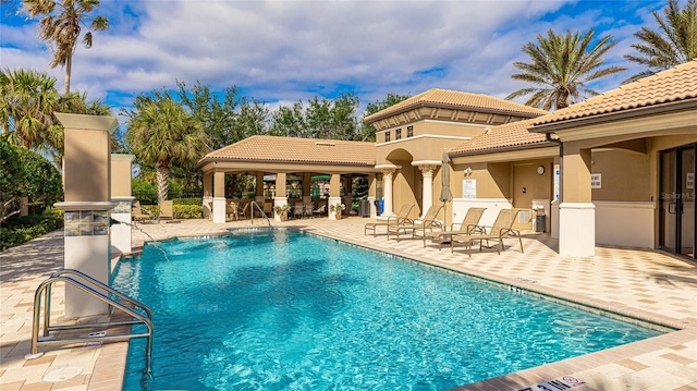 view of swimming pool with pool water feature and a patio area