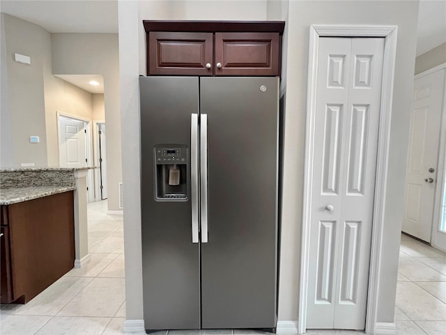 kitchen featuring light stone countertops, stainless steel fridge with ice dispenser, and light tile patterned floors