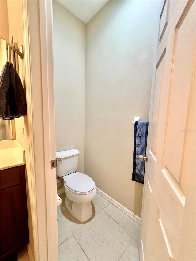 bathroom with toilet, vanity, and tile patterned floors