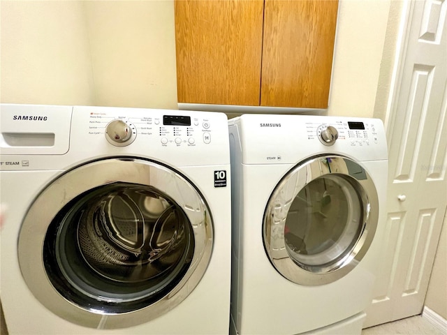 clothes washing area with washing machine and clothes dryer and cabinets