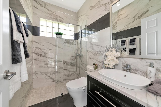 bathroom featuring a tile shower, tile patterned flooring, toilet, vanity, and tile walls