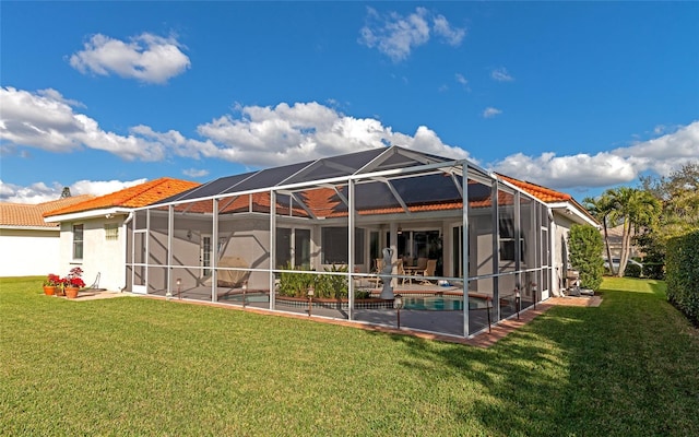 rear view of house with glass enclosure, a patio area, and a lawn