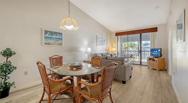 dining space featuring light hardwood / wood-style floors and high vaulted ceiling