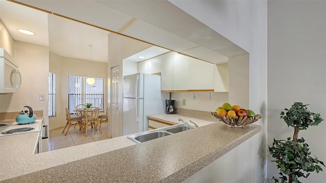 kitchen with white appliances, sink, decorative light fixtures, white cabinetry, and light tile patterned flooring