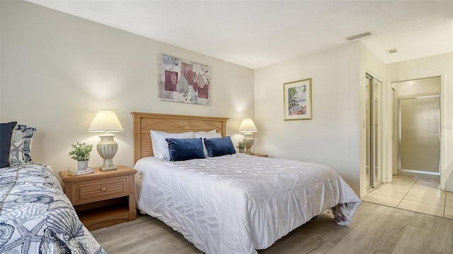 bedroom with a closet, a textured ceiling, and light wood-type flooring