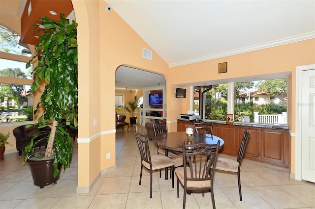 tiled dining space with high vaulted ceiling and ornamental molding