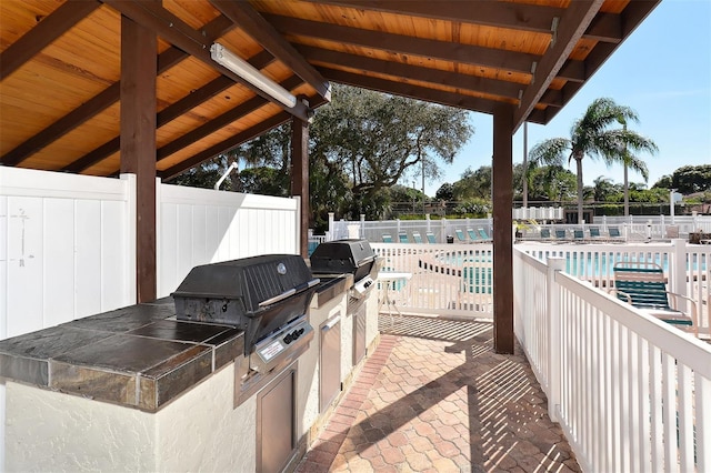 view of patio / terrace featuring an outdoor kitchen, a grill, and a community pool