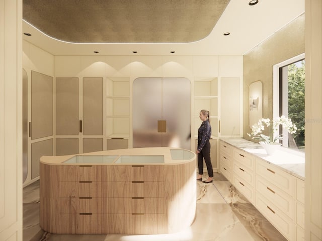 bathroom featuring marble finish floor, vanity, a freestanding bath, and recessed lighting