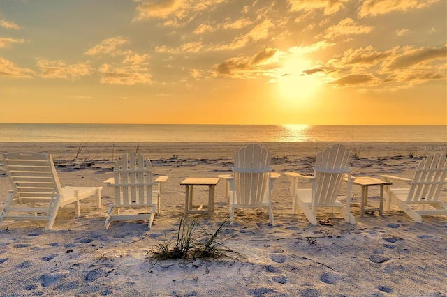 yard at dusk featuring a beach view and a water view