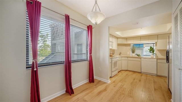 kitchen featuring pendant lighting, a healthy amount of sunlight, white appliances, and light wood-type flooring