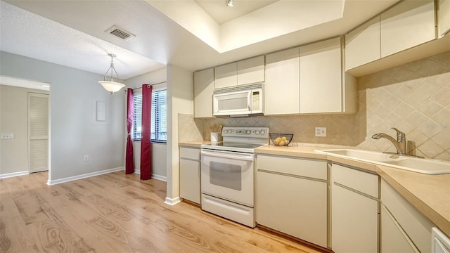 kitchen with sink, tasteful backsplash, pendant lighting, light hardwood / wood-style floors, and white appliances