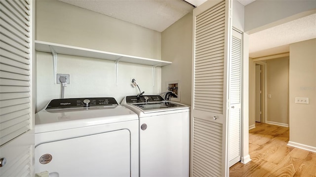 clothes washing area featuring a textured ceiling, light wood-type flooring, and washing machine and clothes dryer