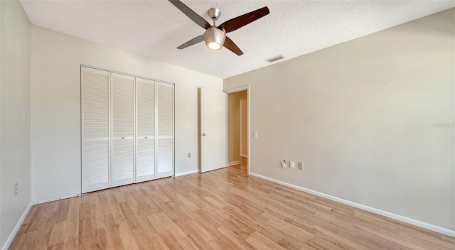 unfurnished bedroom with a textured ceiling, a closet, light hardwood / wood-style flooring, and ceiling fan